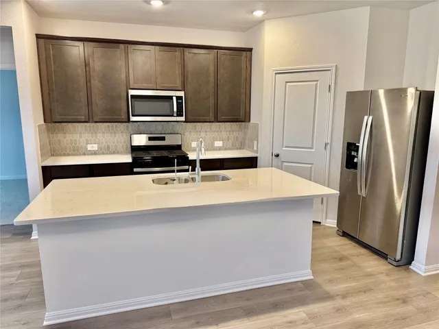 a kitchen with stainless steel appliances a refrigerator microwave stove sink and cabinets