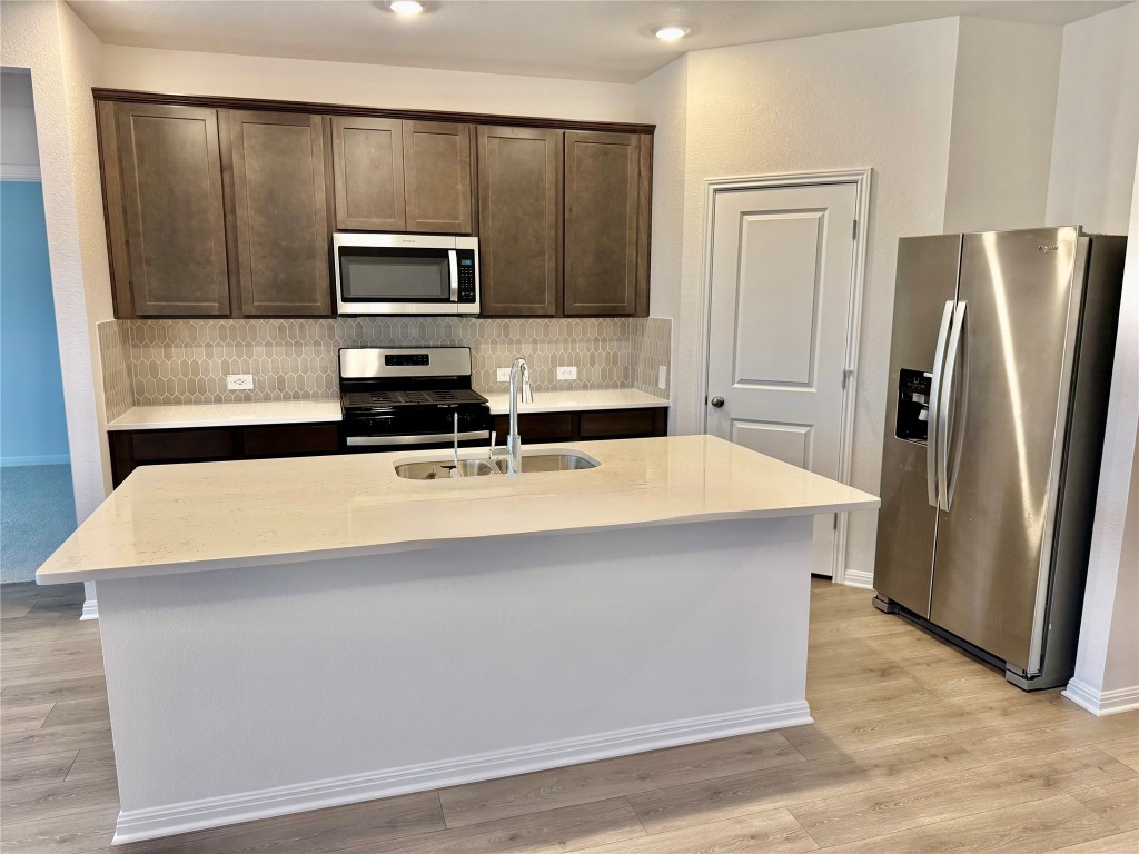 318 Texas Agate Drive Kyle, TX 78640 - Photo 2 of 7 a kitchen with stainless steel appliances a refrigerator microwave stove sink and cabinets
