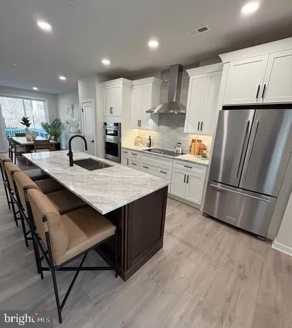 a kitchen with stainless steel appliances granite countertop a refrigerator a stove a sink a dining table and chairs