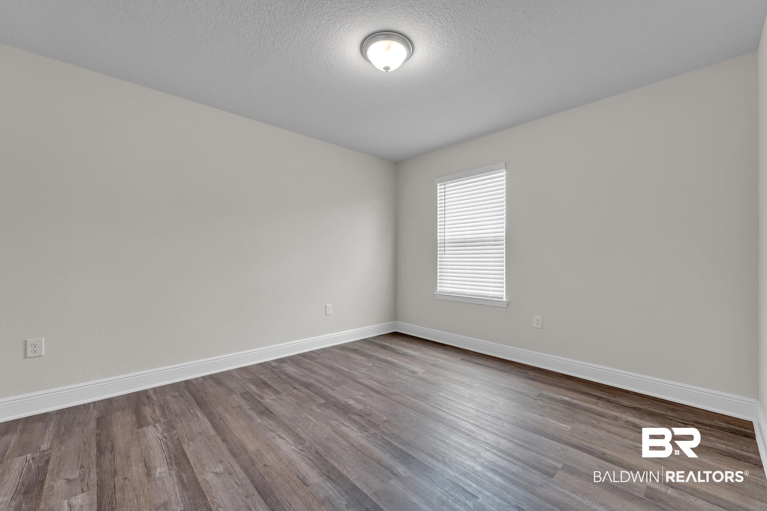 24460 Ringneck Loop Elberta, AL 36530 - Photo 32 of 46 Spare room with a textured ceiling, dark wood-style flooring, and baseboards