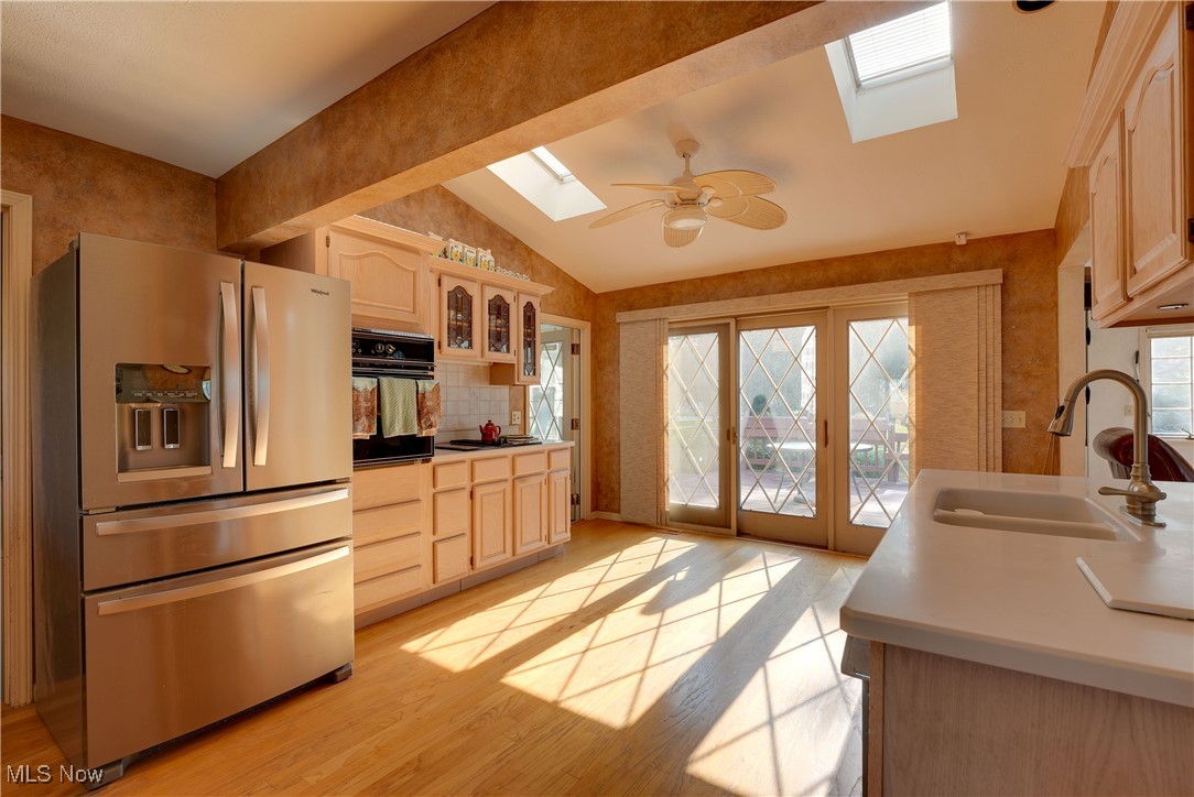 4939 Shankland Road Willoughby, OH 44094 - Photo 6 of 24 Kitchen with a skylight, stainless steel refrigerator with ice dispenser, vaulted ceiling, light brown cabinets, and light wood-style flooring