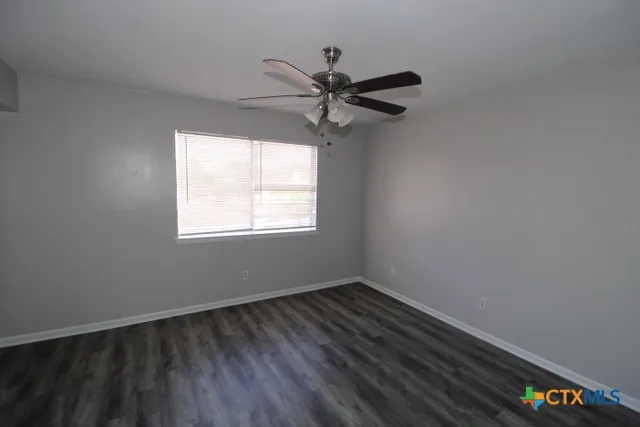 a view of a room with wooden floor fan and windows