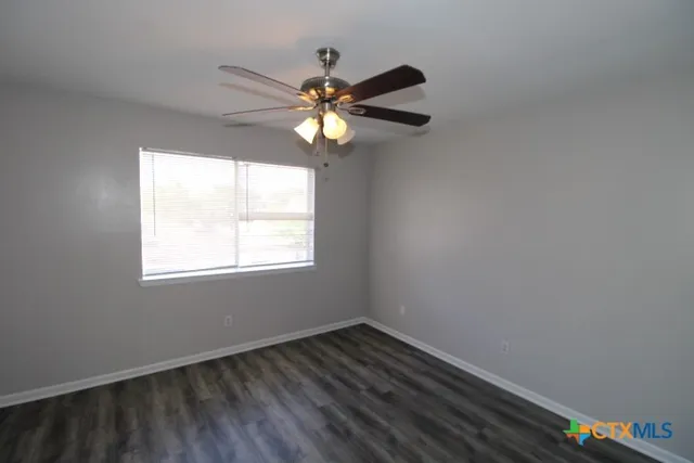 a view of an empty room with chandelier fan and wooden floor
