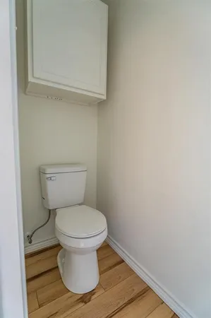 a white toilet sitting next to a white wall