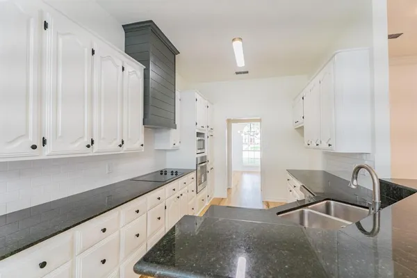 a kitchen with granite countertop white cabinets and sink