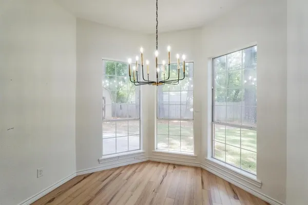 a view of a room with wooden floor chandelier and windows