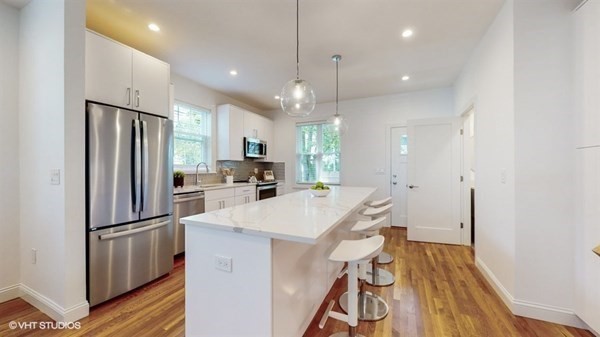a kitchen with refrigerator a sink and wooden floor