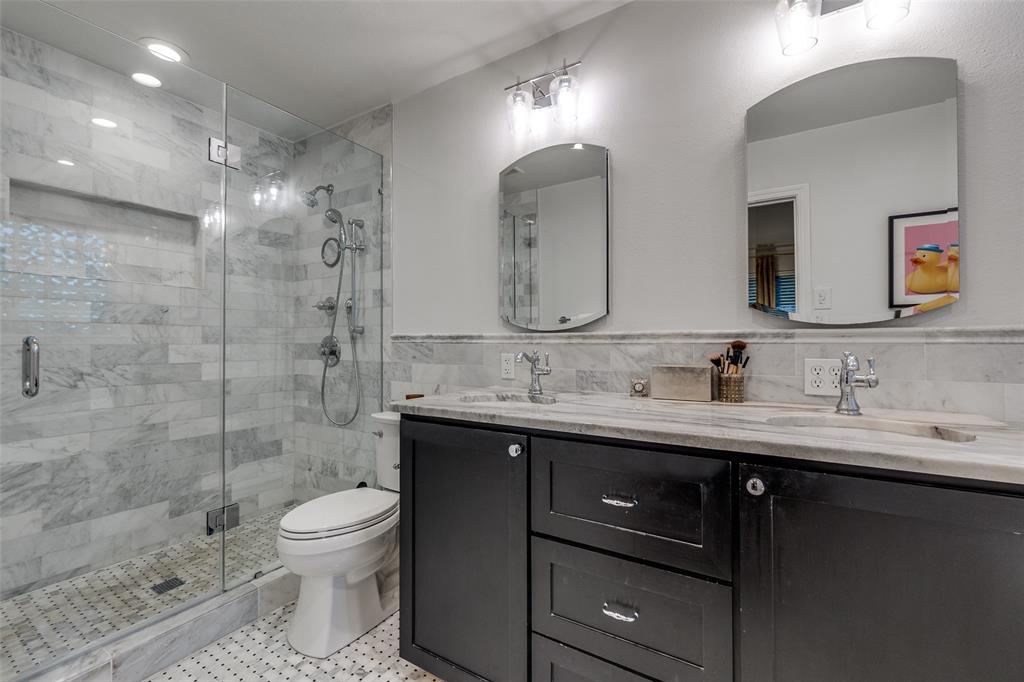 4159 Clover Lane Dallas, TX 75220 - Photo 16 of 25 Full bathroom featuring tile walls, double vanity, a stall shower, toilet, and wainscoting