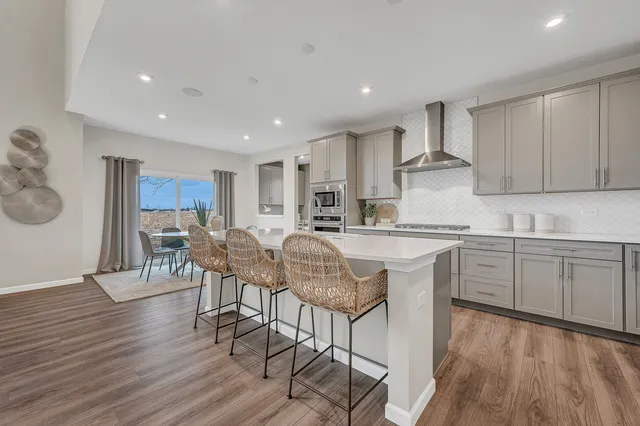 a kitchen with stainless steel appliances granite countertop a stove a sink a refrigerator with a dining table and chairs