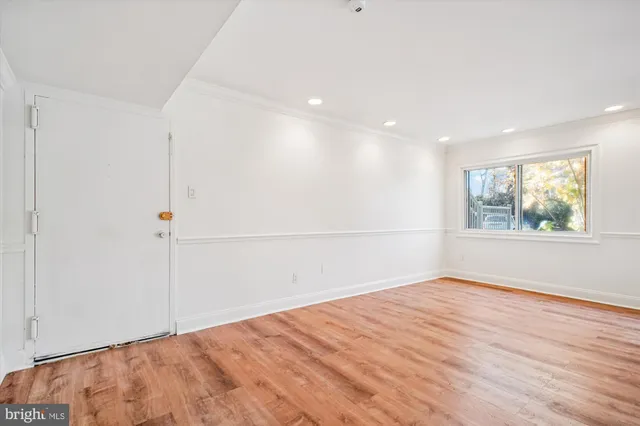 an empty room with wooden floor and window