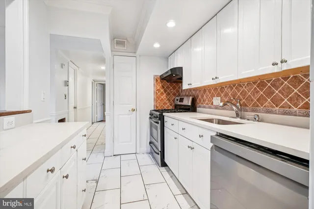 a kitchen with a sink dishwasher stove and white cabinets