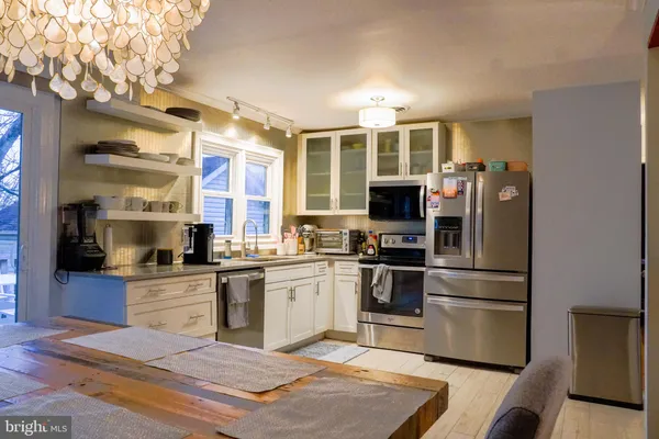 a kitchen with stainless steel appliances granite countertop a refrigerator oven a sink dishwasher and white cabinets with wooden floor