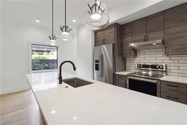 a kitchen with a stove a refrigerator a sink and wooden floor