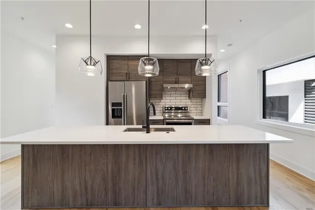 a kitchen with a sink a counter top space stainless steel appliances and wooden floor