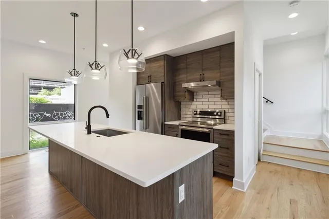 a kitchen with a sink a counter space appliances and cabinets