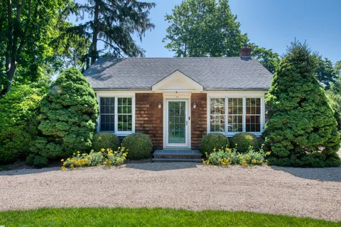 a front view of a house with a yard and potted plants