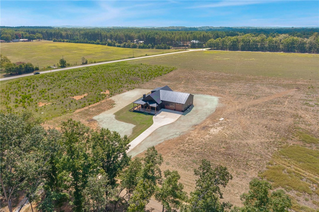 384 Jim Smith Road Pendleton, SC 29670 - Photo 41 of 48 A modern metal-roofed home sits nestled within expansive acreage bordered by mature trees.