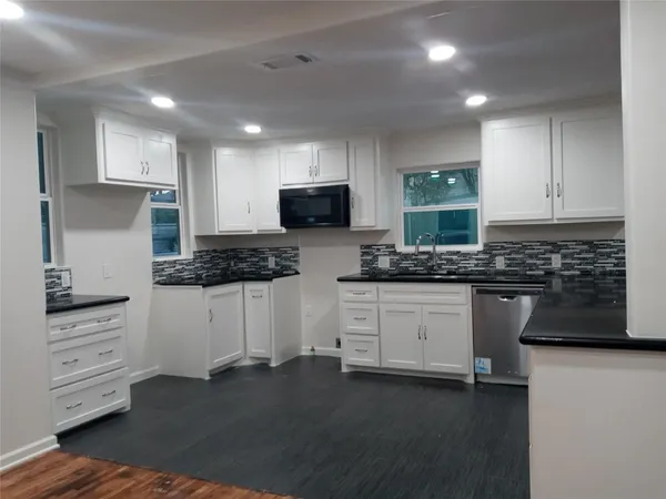 a kitchen with white cabinets and appliances