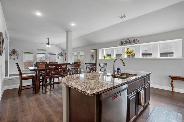 a kitchen that has a lot of cabinets a sink and a wooden floor
