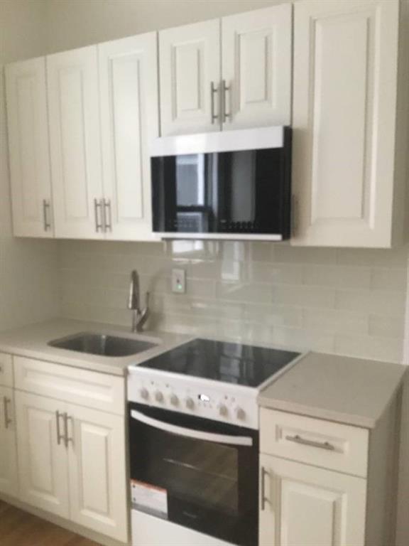 9307 3rd Avenue Brooklyn, NY 11209 - Photo 3 of 23 a kitchen with white cabinets and white appliances