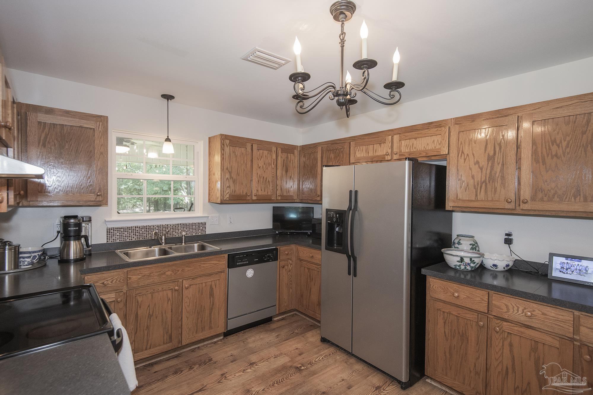 8501 Highway 97 Walnut Hill, FL 32568 - Photo 12 of 55 a kitchen with stainless steel appliances granite countertop a refrigerator a sink dishwasher a stove and a dining table with wooden floor