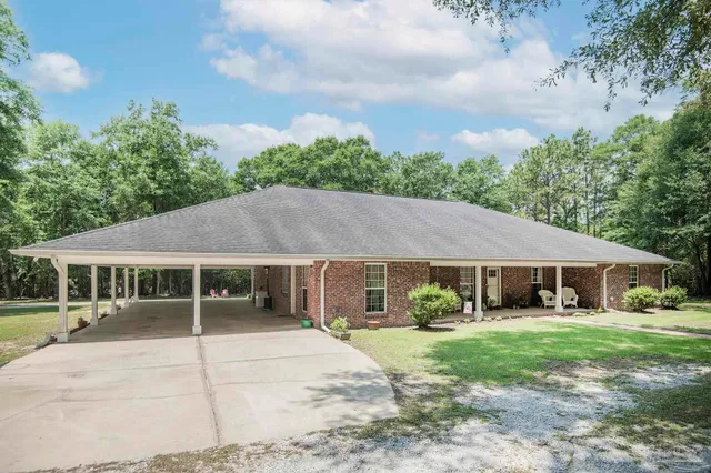 a view of a white house with a yard plants and large tree