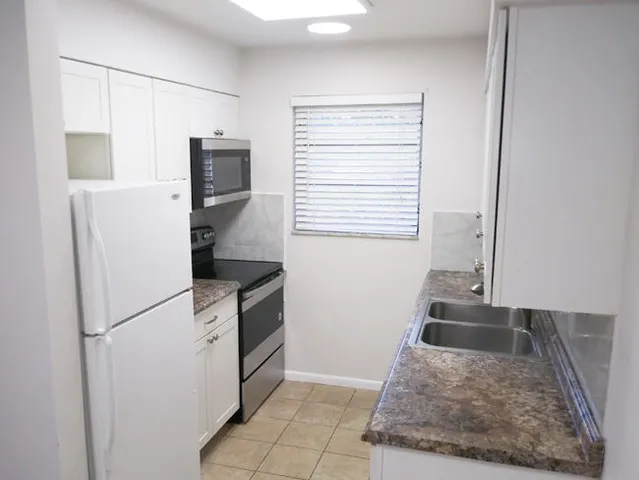 a kitchen with granite countertop a refrigerator and a sink