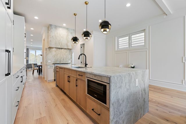 a large kitchen with stainless steel appliances a large center island and a wooden floor