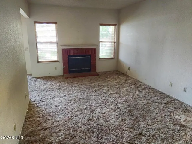 a view of an empty room with a fireplace and a window