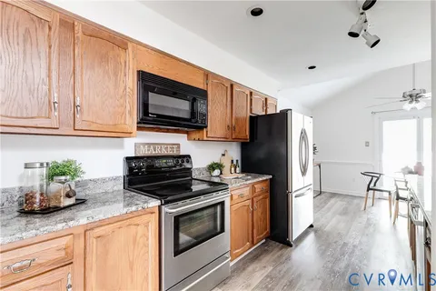 a kitchen with stainless steel appliances granite countertop a stove a sink dishwasher and a refrigerator with wooden floor