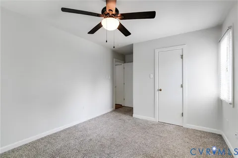 an empty room with a ceiling fan and a window