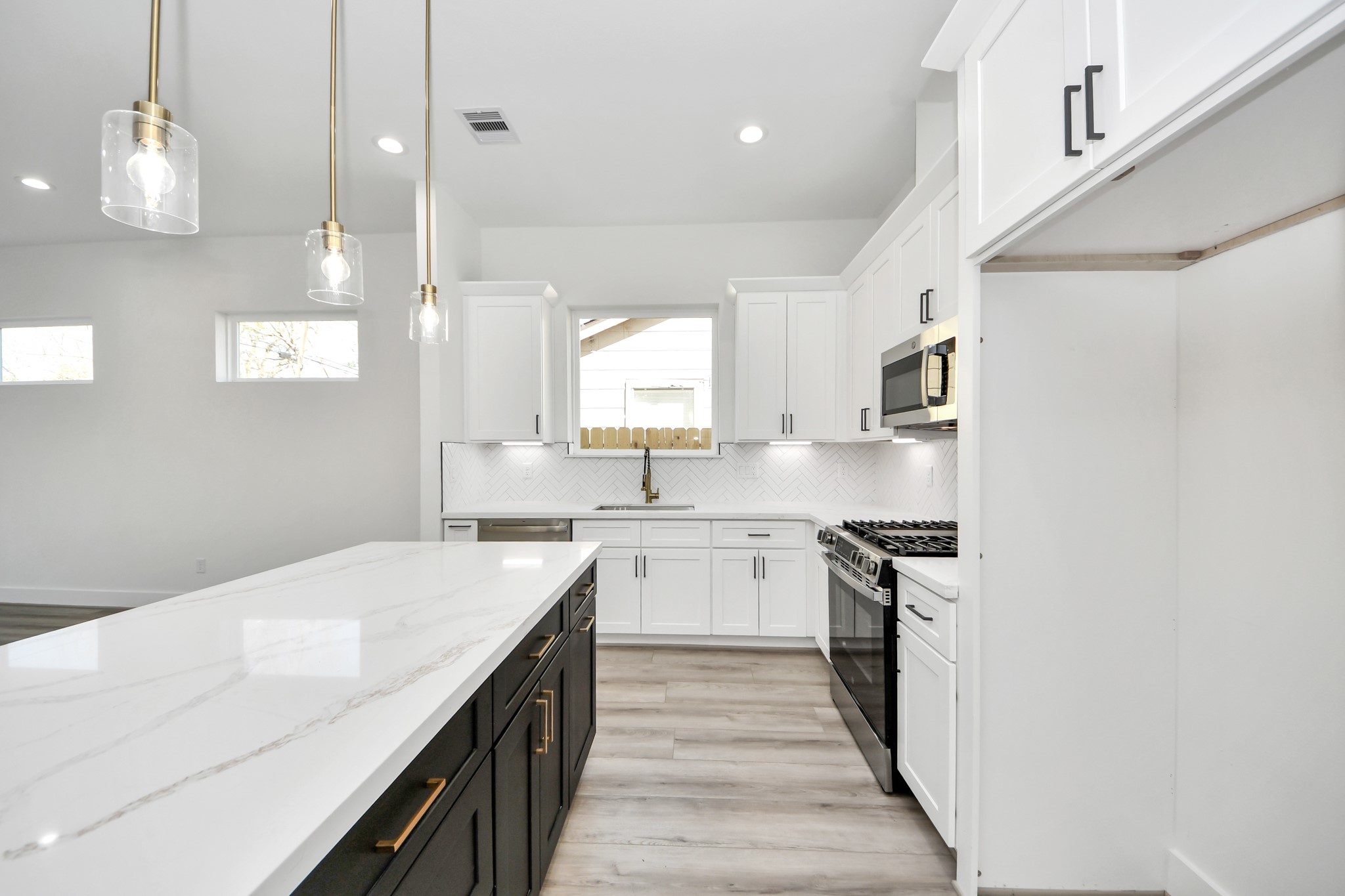 7012 St Augustine Street Houston, TX 77021 - Photo 7 of 45 a kitchen with a sink dishwasher a stove and white cabinets with wooden floor