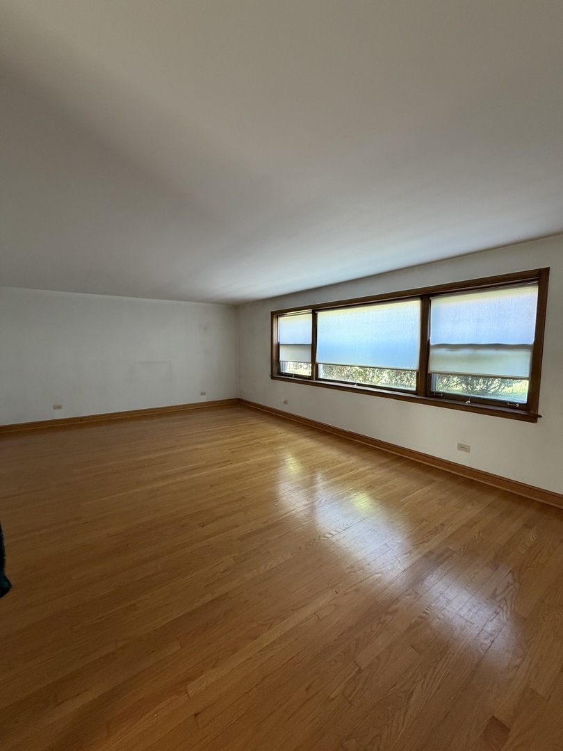 7228 South Phillips Avenue, Unit G Chicago, IL 60649 - Photo 2 of 10 a view of an empty room with wooden floor and a window