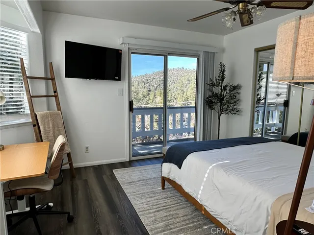 a bedroom with a bed a flat screen tv and a large window