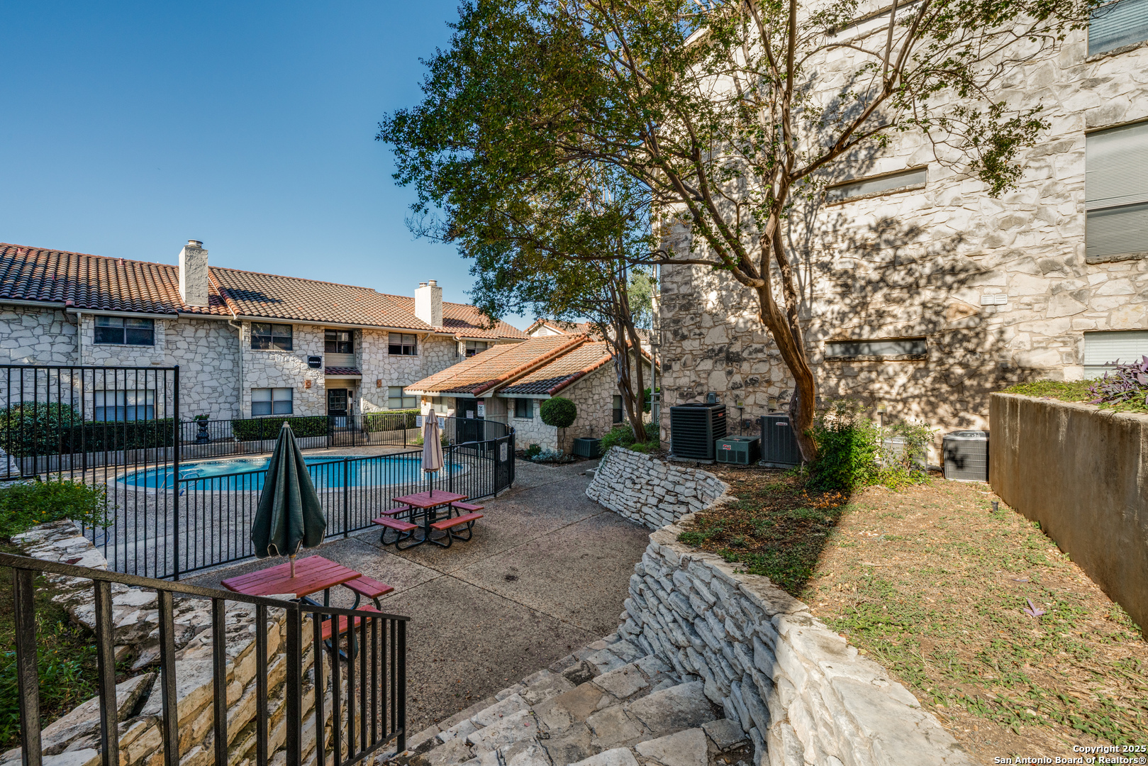 7738 Chambers Road, Unit 903 San Antonio, TX 78229 - Photo 21 of 22 a view of a patio with table and chairs potted plants and large tree