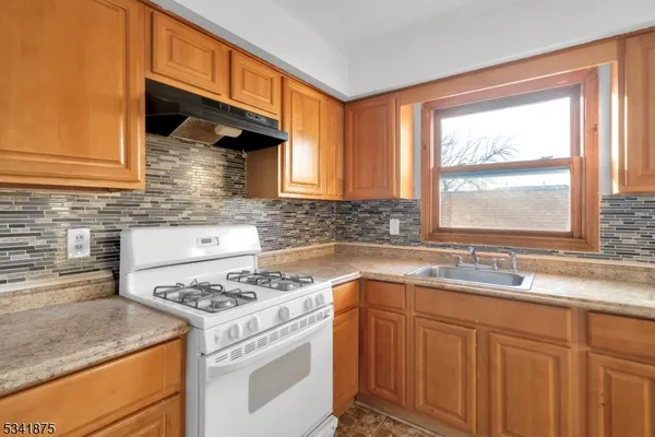 a kitchen with granite countertop a sink stove and cabinets