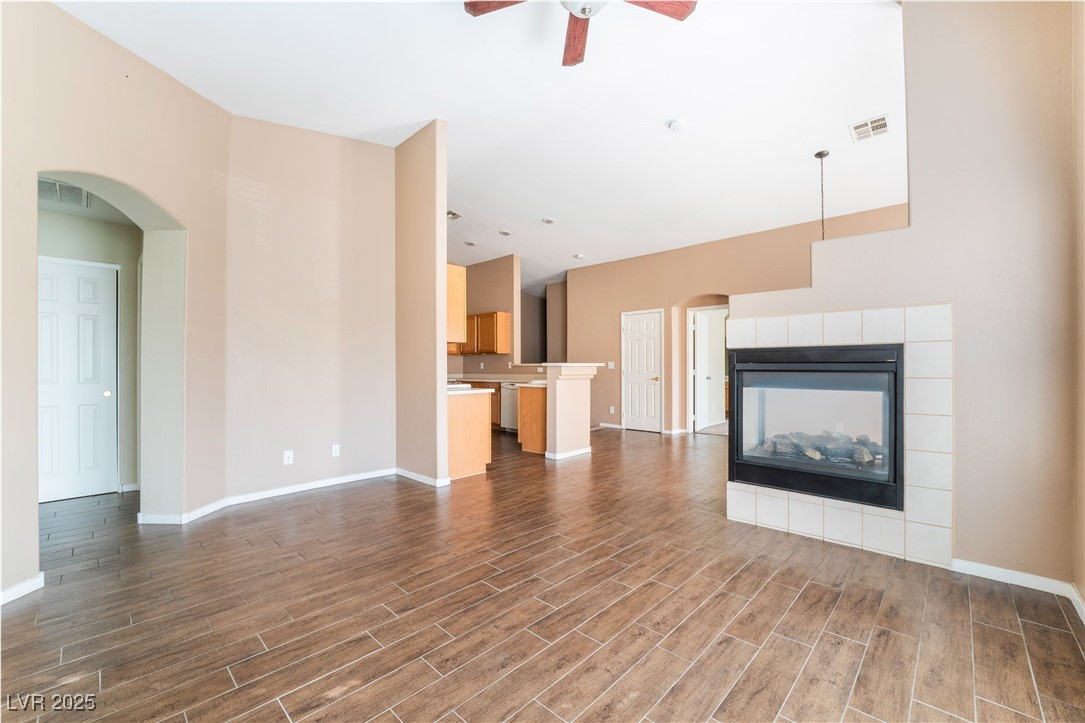 1570 Rusty Ridge Lane Henderson, NV 89002 - Photo 15 of 35 Unfurnished living room featuring arched walkways, a ceiling fan, visible vents, wood finished floors, and baseboards