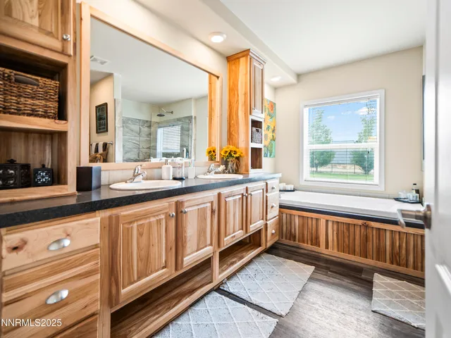 a bathroom with sink a large mirror and a bathtub next to a window