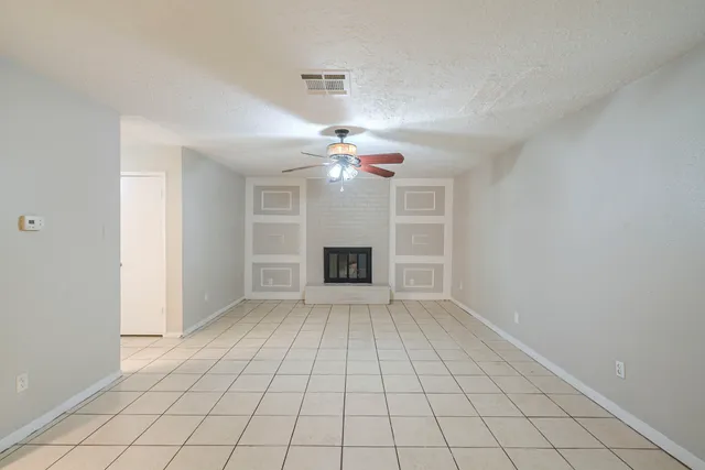 a view of an empty room with a fireplace and a chandelier fan
