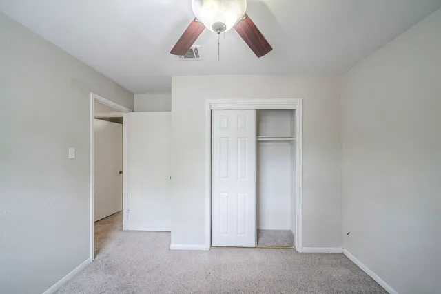 a view of an empty room with chandelier fan