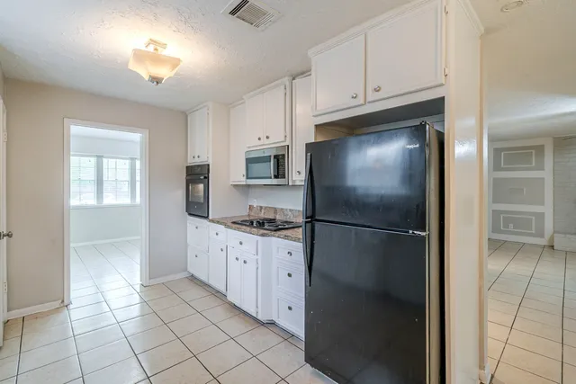a kitchen with stainless steel appliances granite countertop a refrigerator a sink and white cabinets
