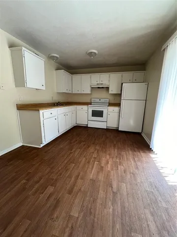 a kitchen with wooden floors and white appliances
