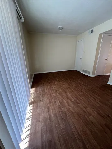 a view of an empty room with wooden floor and white walls
