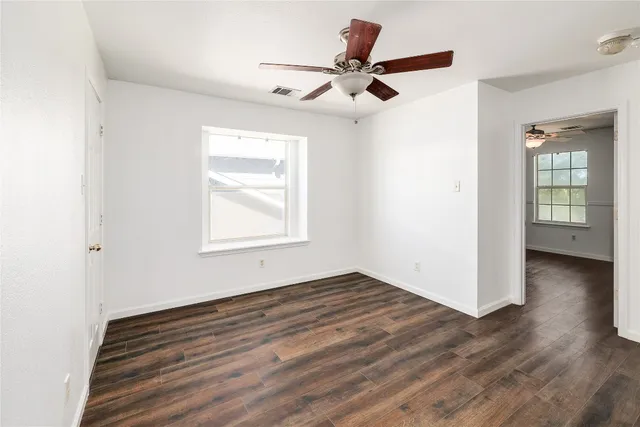 a view of empty room with wooden floor and fan