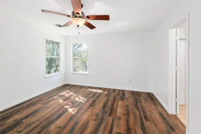 a view of empty room with wooden floor and fan
