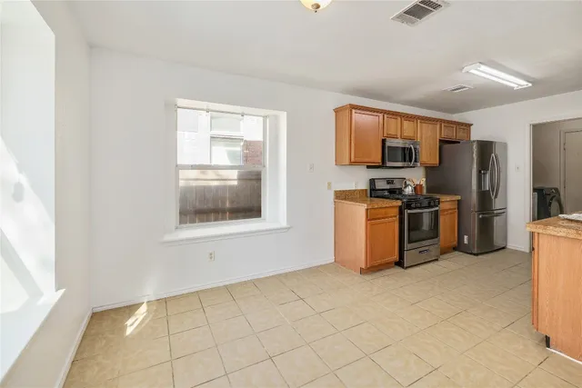 a kitchen with stainless steel appliances a stove a sink a microwave a refrigerator and cabinets