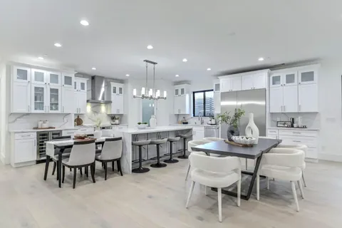 a kitchen with a dining table chairs wooden floor appliances and cabinets
