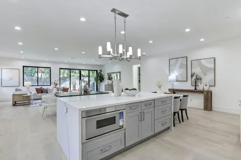 a kitchen with kitchen island granite countertop lots of white cabinets appliances and a dining table