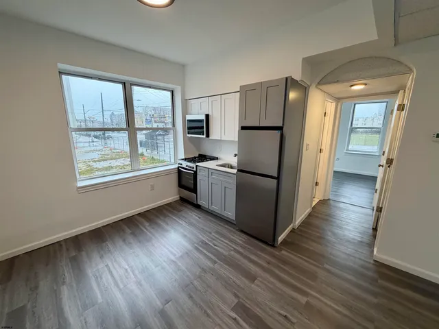 a kitchen with stainless steel appliances granite countertop a refrigerator a sink and wooden floors