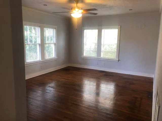 an empty room with wooden floor and windows
